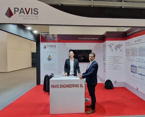 Zwei Männer im Anzug stehen an einem PAVIS-Messestand auf rotem Teppich, Banner und Infowände im Hintergrund.